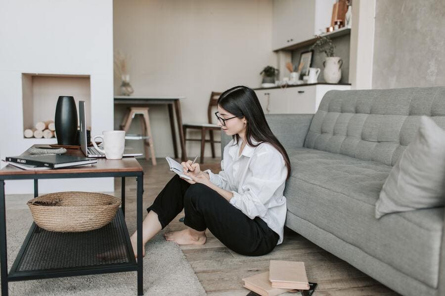 Woman sitting on her living room floor writing in a notebook