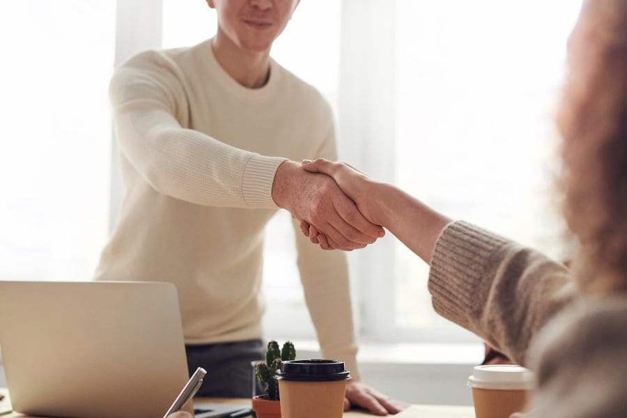 man and woman shaking hands over a desk